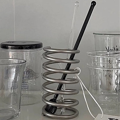 Stainless steel brush holder with an intricate spiral pattern, designed to be both functional and visually appealing in any setting.