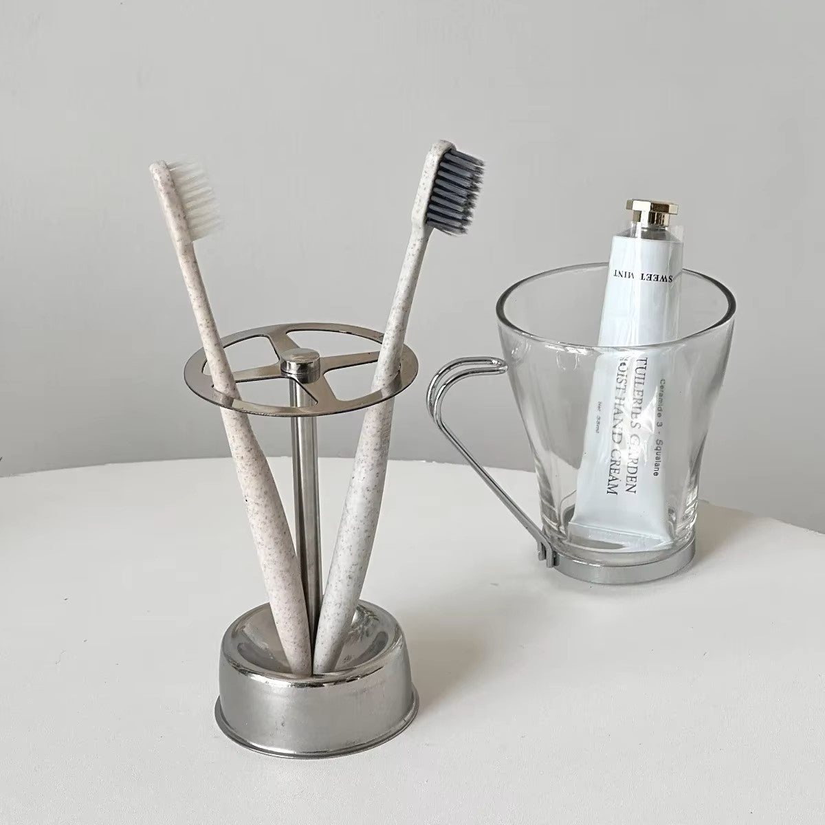 Sleek stainless steel brush holder organizing toothbrushes on a countertop. Features a minimalist design with four grids.