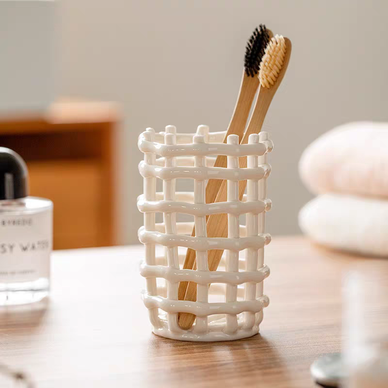 A ceramic toothbrush holder with a hollow bottom for drainage, perfect for keeping toothbrushes dry and organized in a sleek bathroom setting.