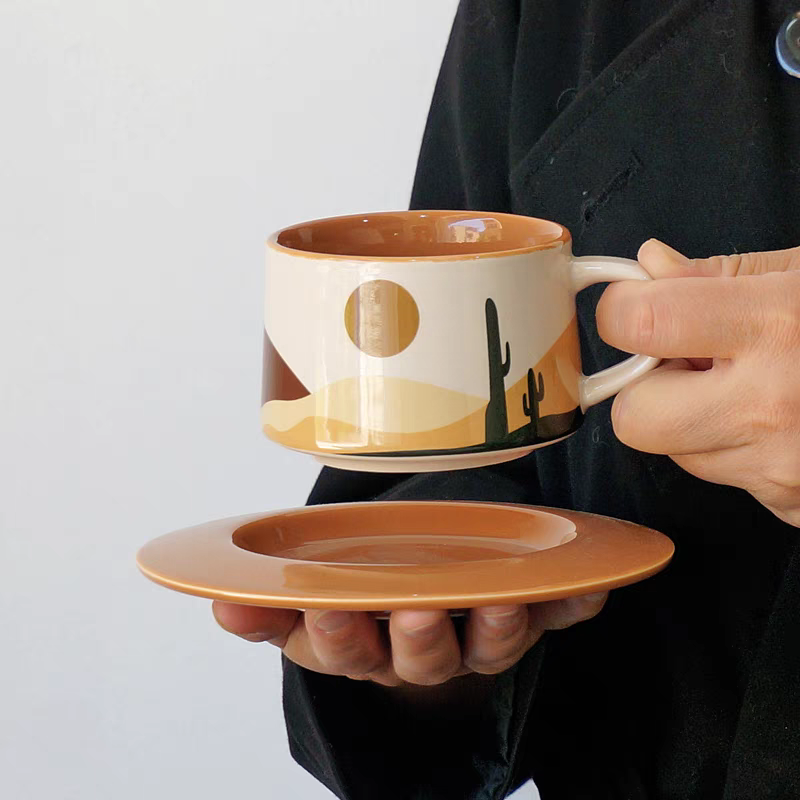 Ceramic coffee cups with matching plates featuring desert patterns, perfect for enhancing Scandinavian and minimalist interiors with artistic drinkware.