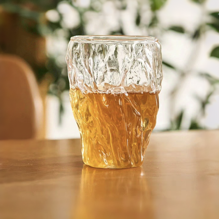 Crystal glass cup with irregular design, highlighting the natural hues of tea, suitable for hot or iced beverages.