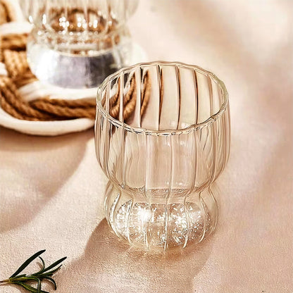 A clear glass cup with a wave rim, highlighting its sturdy, dishwasher-safe material and contemporary style.