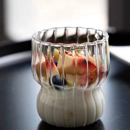 A clear ribbed glass cup holding a fruit smoothie, ideal for drinks in contemporary kitchen settings.