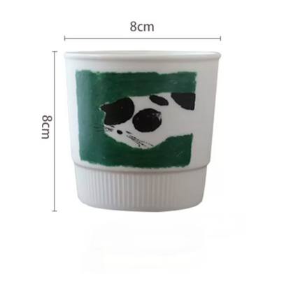 Whimsical handmade pottery mug showcasing a cat curled up for a nap. Soft Nordic colors and minimalist style make it a cozy and cute drinkware choice for any stylish kitchen or desk.