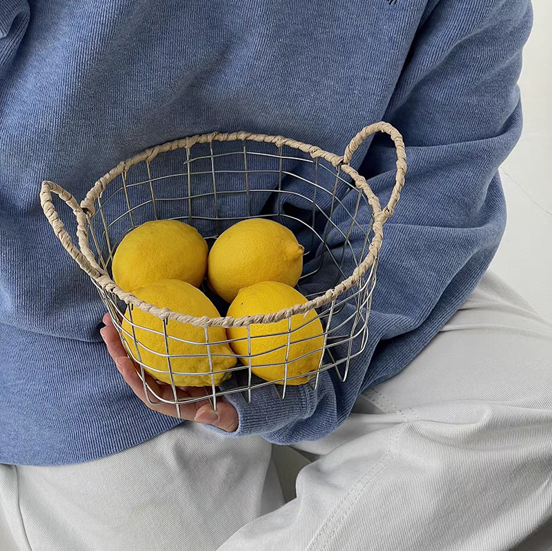 Scandinavian design round woven metal wire basket filled with fruits, emphasizing its eco-friendly and decorative features.