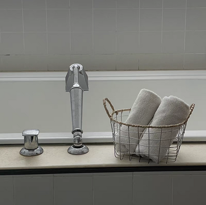 Round woven metal wire storage basket with handles used to store rolled towels, adding a touch of Scandinavian minimalism to the bathroom.